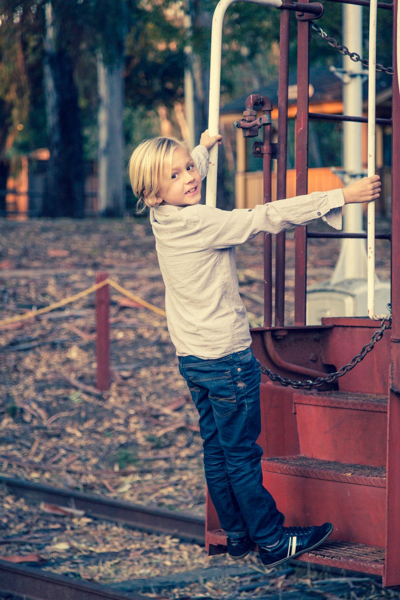 Young boy grinning back at the camera as he climbs the steps of a red caboose at Los Carneros in Goleta