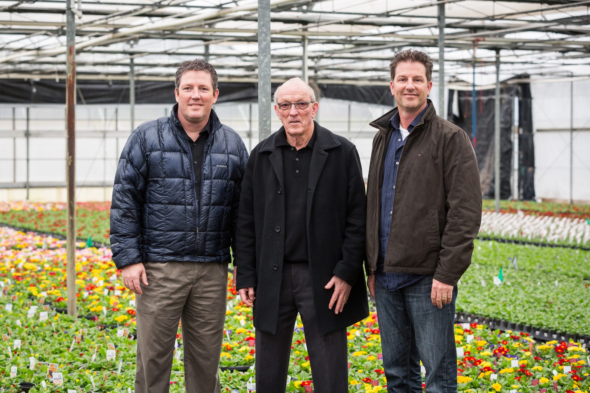 Three nursery partners standing together in a flowering greenhouse