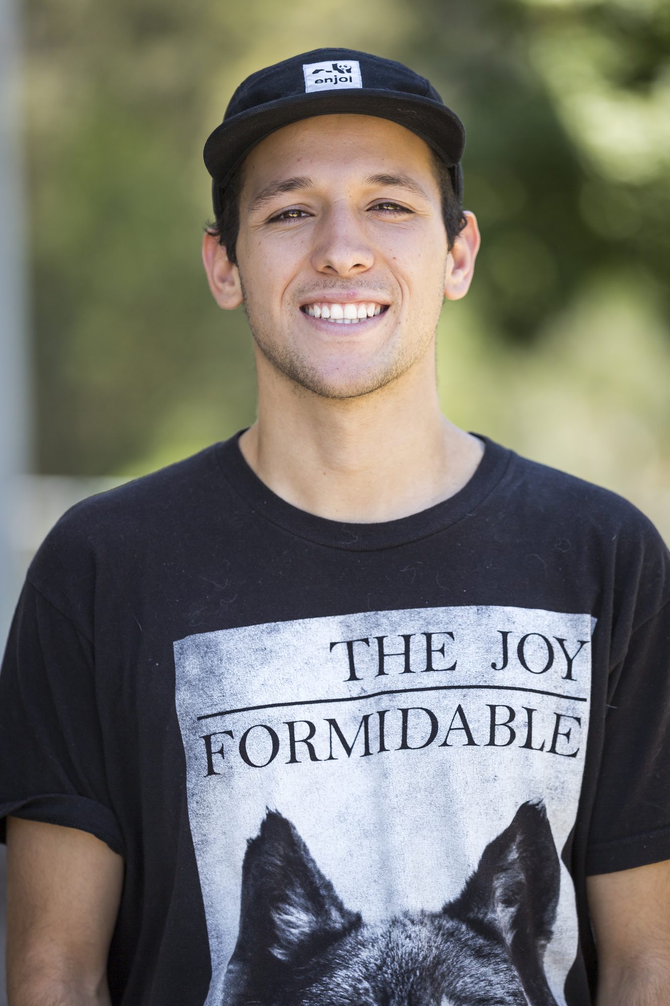 Smiling young man in a baseball cap and graphic tee outdoors