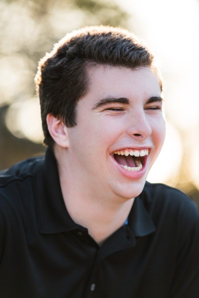 High school senior laughing in front of a dark background