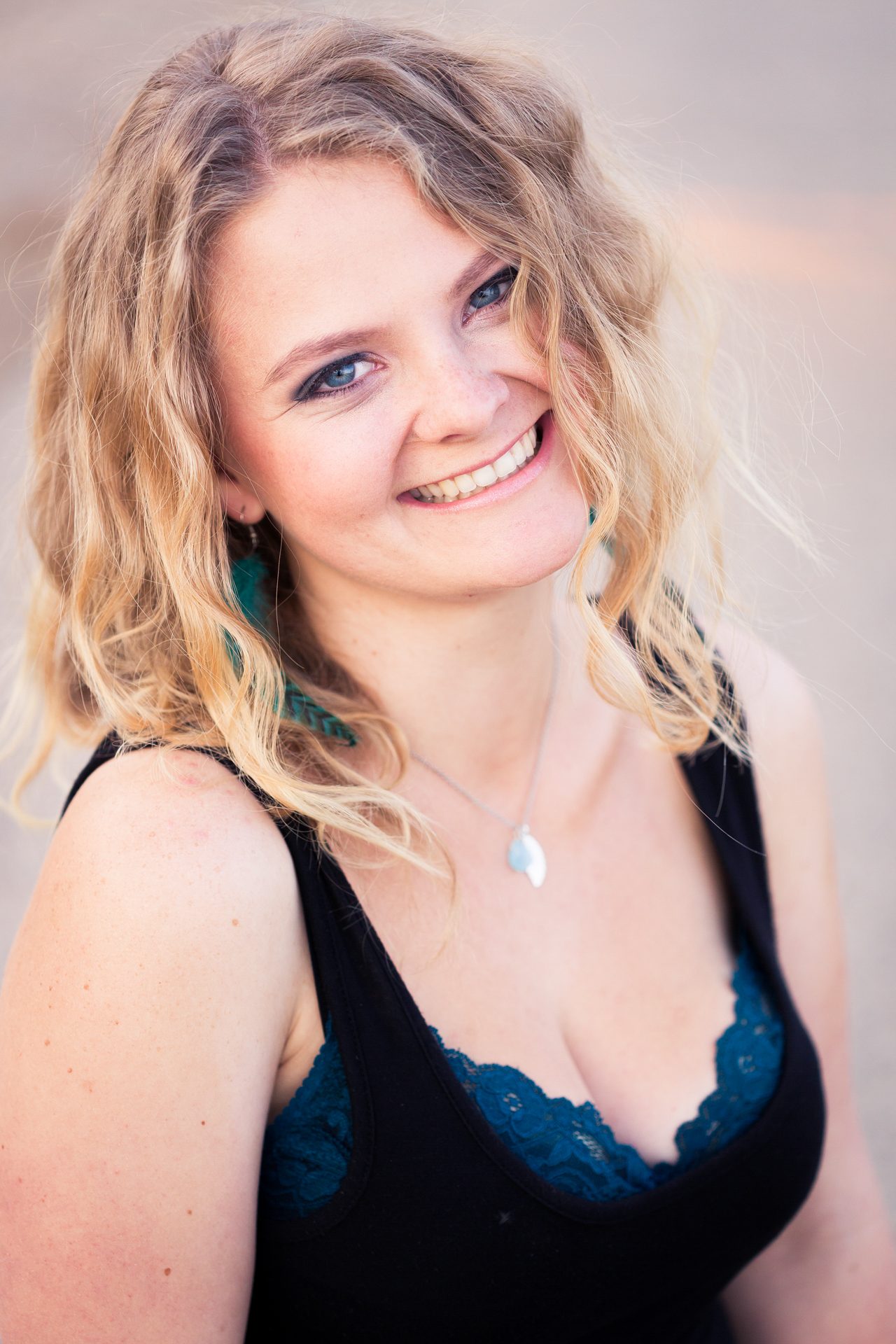 Young woman with curly blonde hair smiling in soft overcast light
