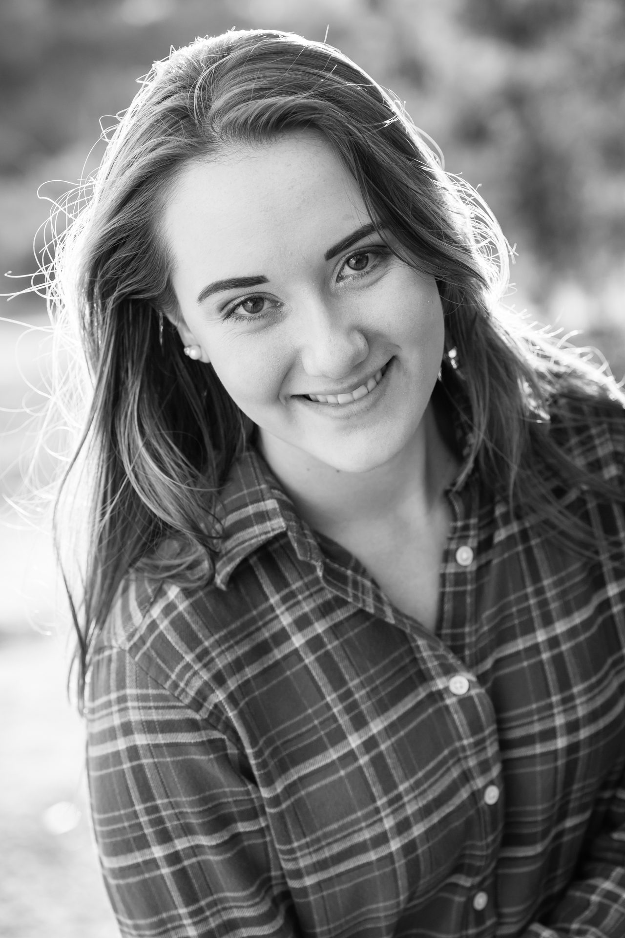 Black and white portrait of a smiling girl in a plaid shirt